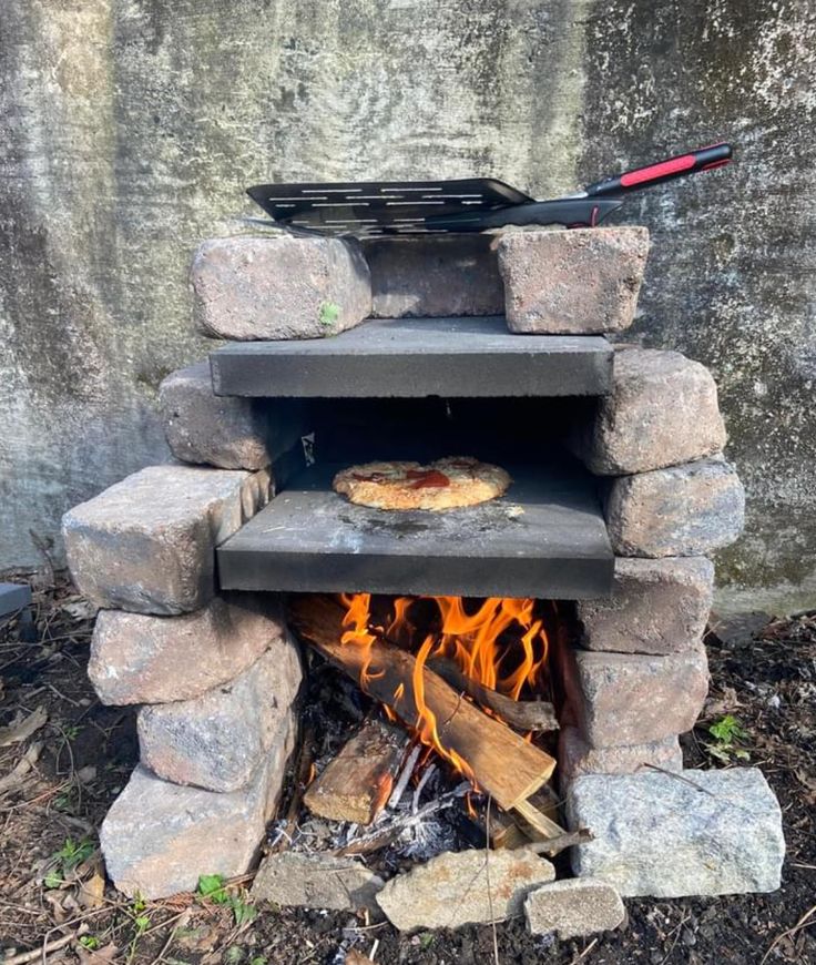 an outdoor pizza oven made out of stone and wood, with flames burning in it