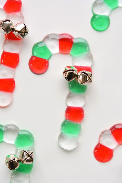 two candy canes with bells on them sitting next to some gummy candies