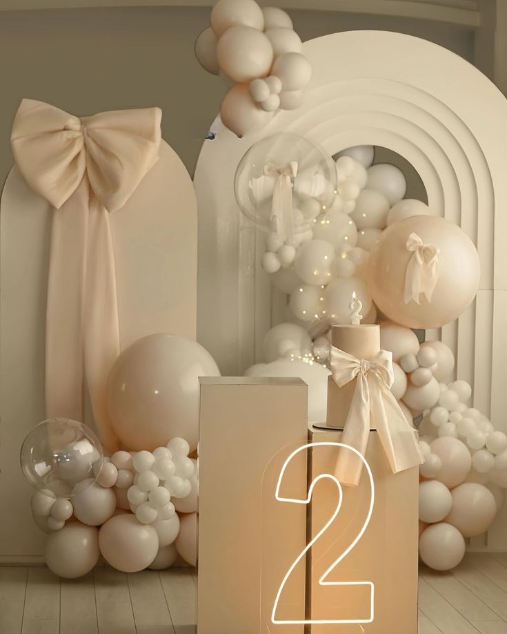 a number two sign next to balloons and other decorations in a room with white walls