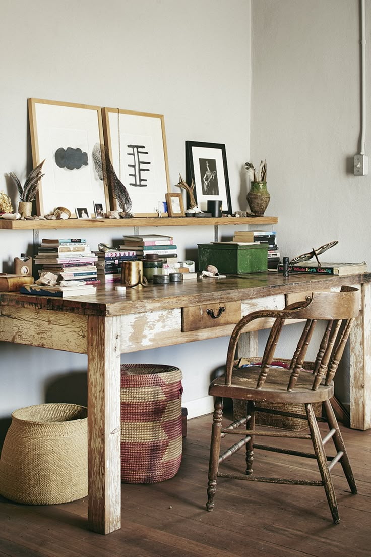 a wooden table topped with lots of books next to a shelf filled with pictures and knick knacks