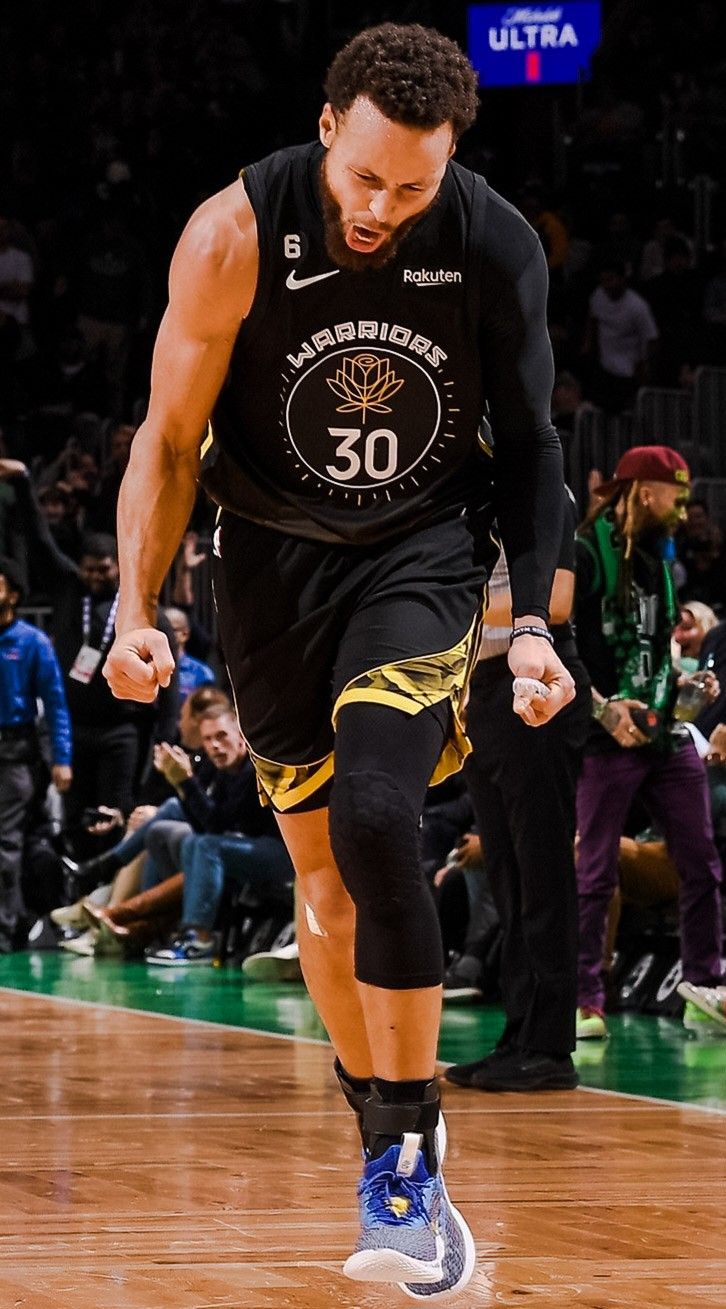 a basketball player dribbling the ball down the court during a game with fans in the stands