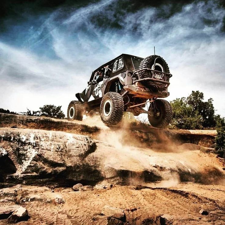 a black four - door truck is jumping over rocks