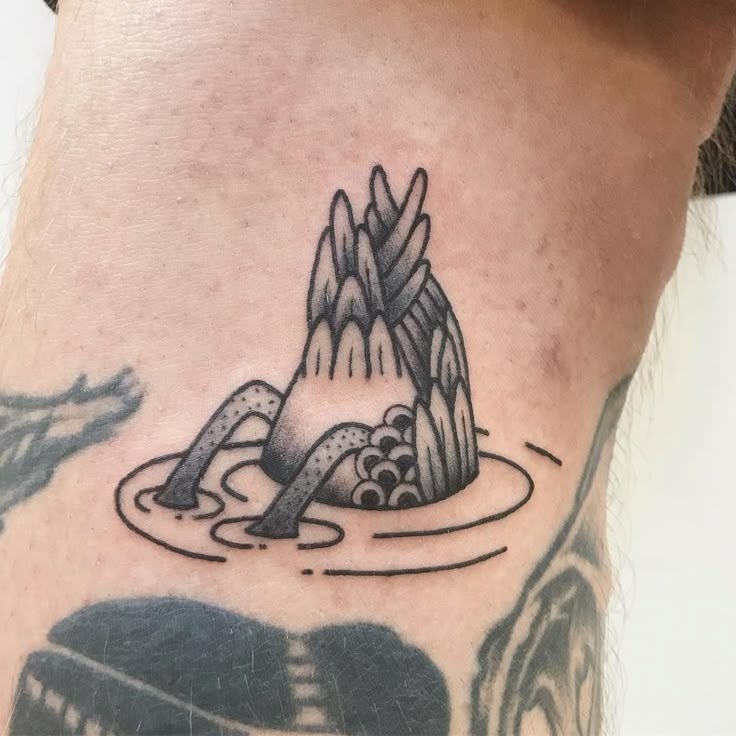 a close up of a person's leg with a tattoo on it and an iceberg in the water