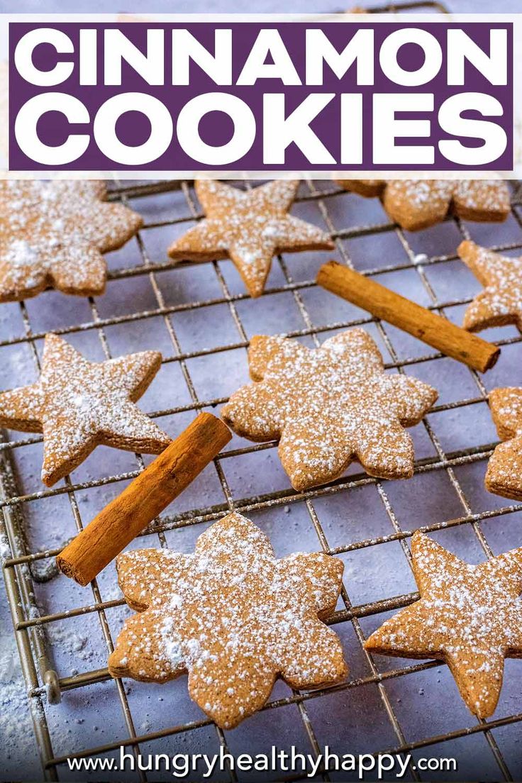 cinnamon cookies on a cooling rack with cinnamon sticks and powdered sugar in the shape of stars