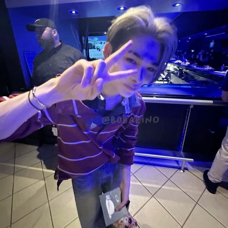 a young man making the peace sign with his fingers while standing in front of a recording studio