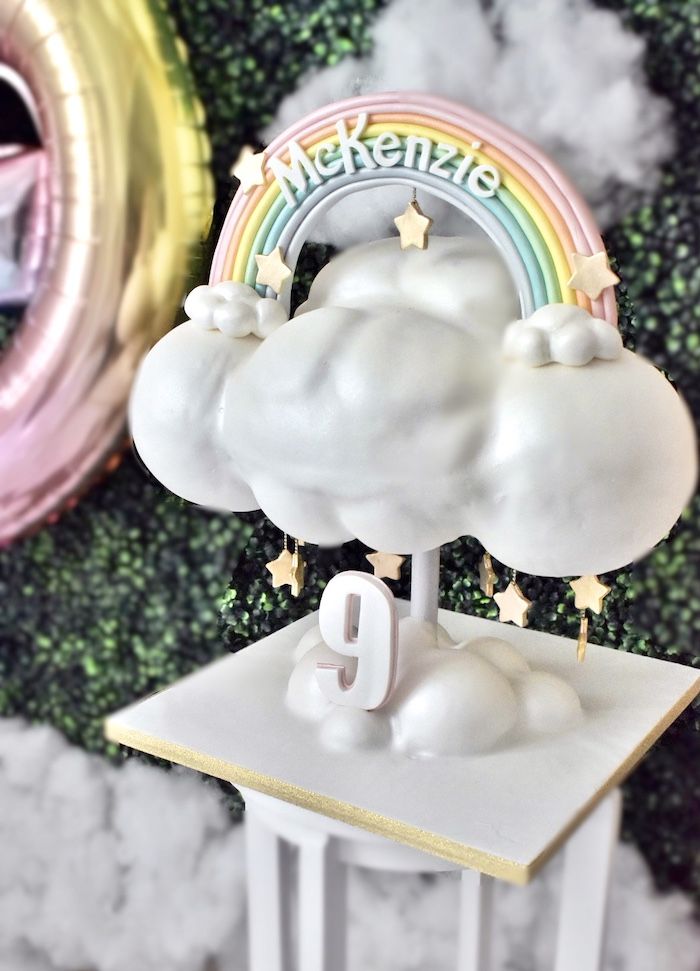 there is a cake that looks like a cloud with a rainbow on top and stars around it