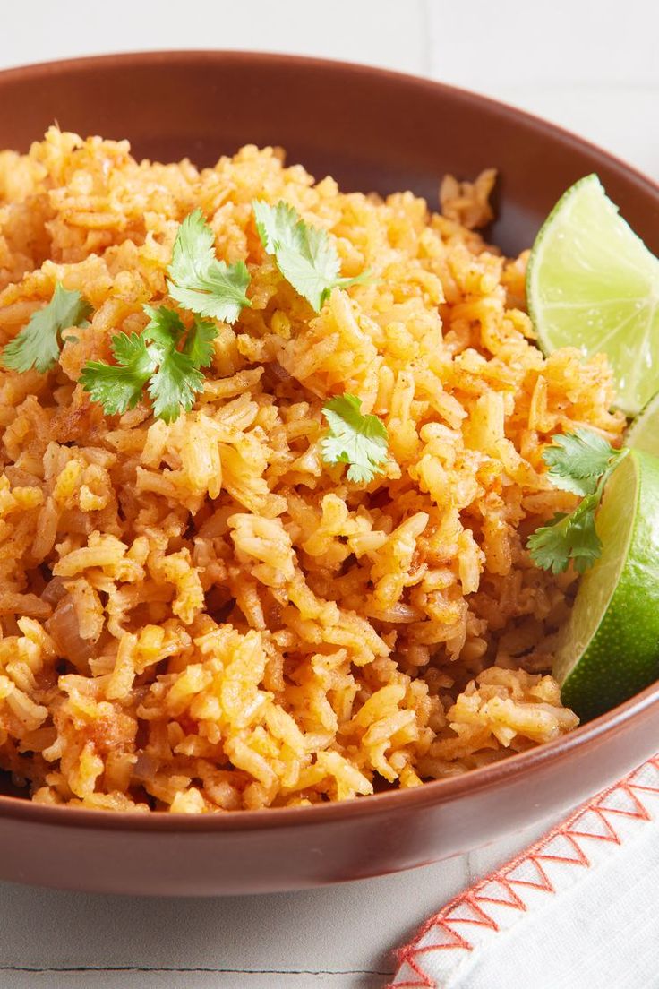 a brown bowl filled with rice, cilantro and lime wedged in it