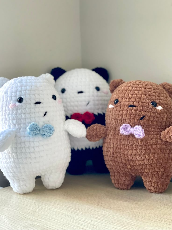 four small stuffed animals are lined up on the shelf together, one is wearing a bow tie