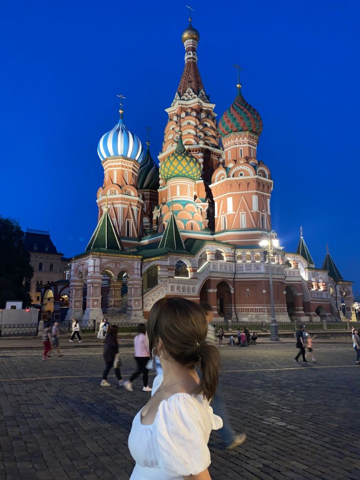 a woman is standing in front of a building with domes on it's sides