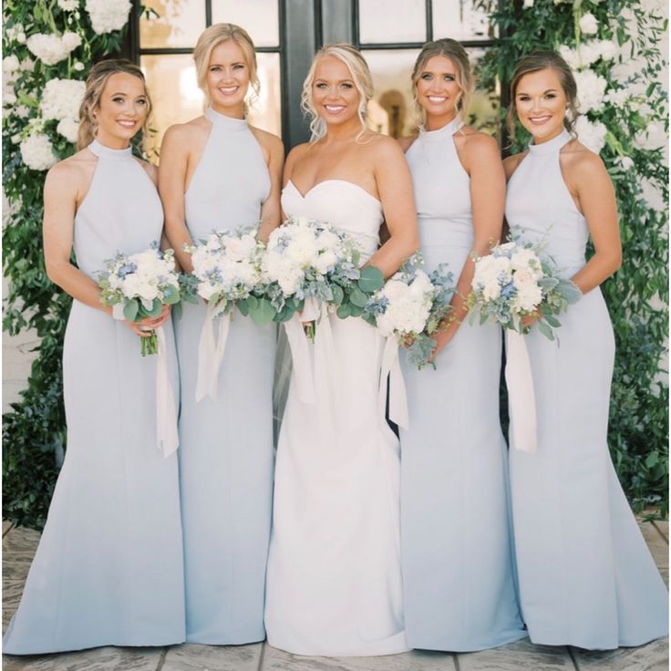 a group of women standing next to each other in front of a building with flowers