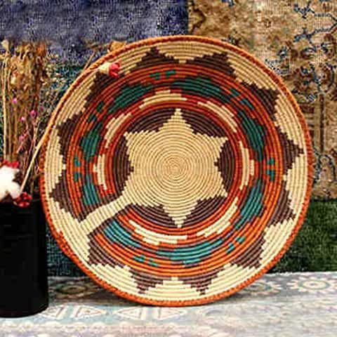 a woven basket sitting on top of a table next to a vase