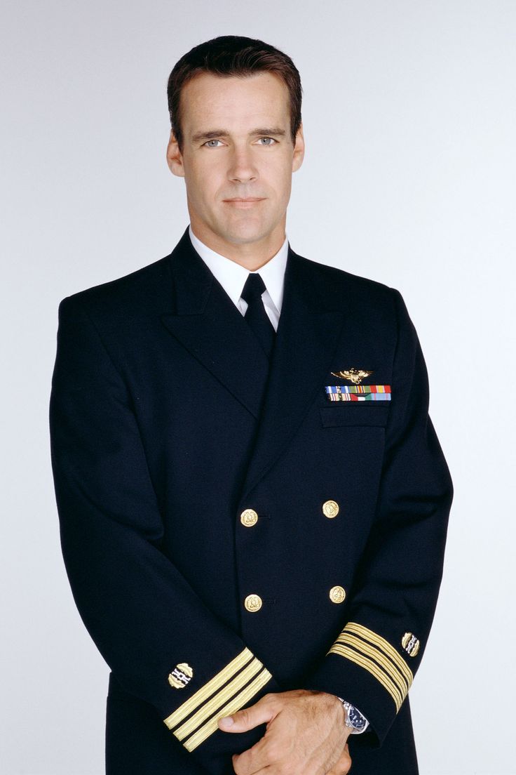 a man in uniform is posing for a photo with his hands on his chest and arms crossed