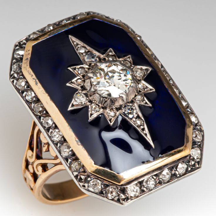 This fantastic circa Victorian era ring features a sterling silver and 18K yellow gold octagonal shaped gallery. The center of the gallery is topped with a diamond accented sterling silver star setting bordered with blue enamel. The star shaped setting is centered with one (1) bead set, old European cut diamond and is bordered with fourteen (15) old mine/rose cut diamonds bead set into the points of the star. The gallery is framed with thirty (30) old mine/singe cut diamonds bead set into sterli Art Deco Enamel Jewelry For Anniversary, Antique Star Ring, Antique Gold Star-shaped Jewelry, Star Sapphire Cabochon Ring, Luxury Elegant Star-shaped Brooches, Luxury Star-shaped Brooch Jewelry, Victorian Diamond Ring, European Cut Diamonds, Rose Cut Diamond