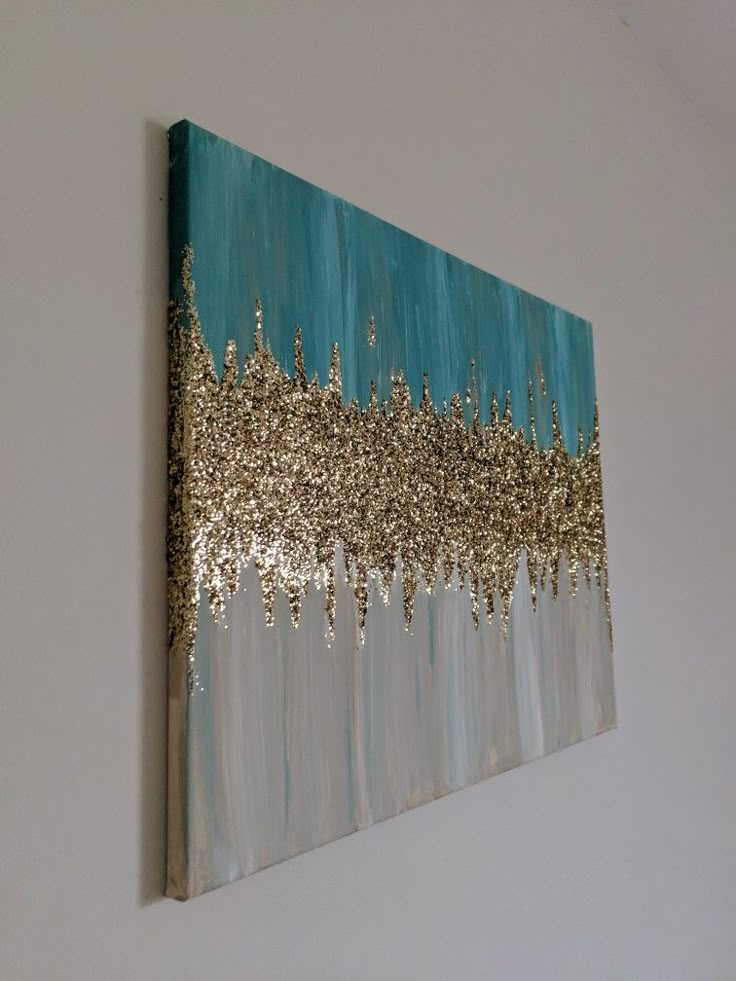 a painting hanging on the wall with gold and blue paint splattered over it