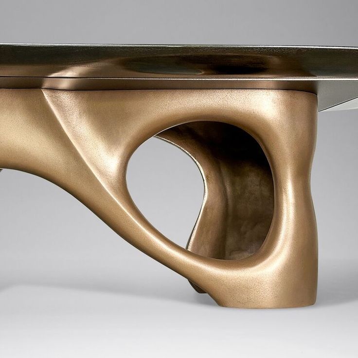 an unusual coffee table made out of bronzed metal with a curved design on the top