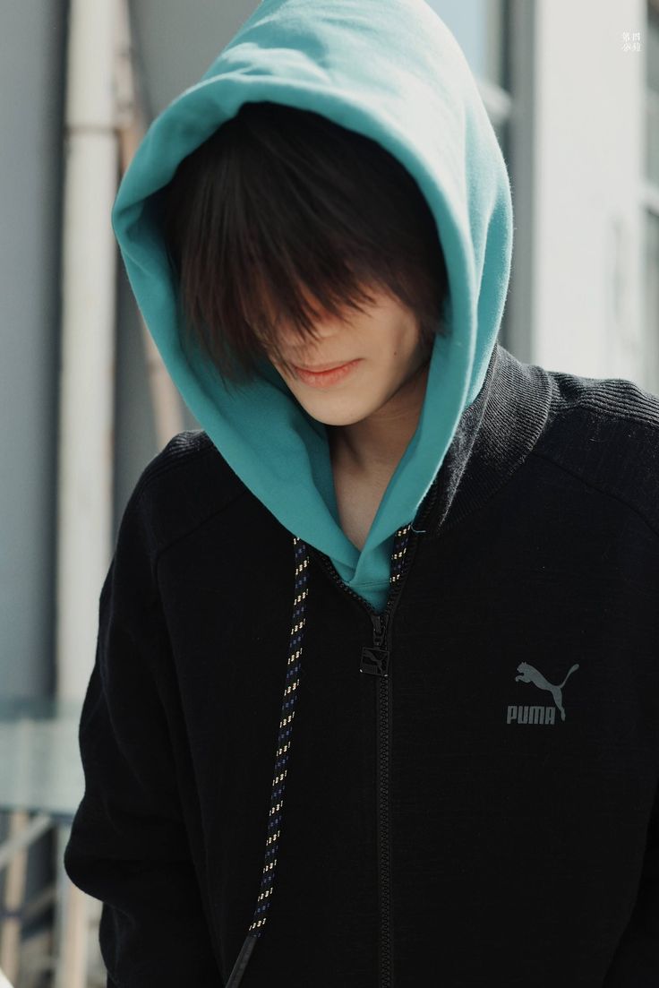 a young man wearing a blue hoodie looking at his cell phone