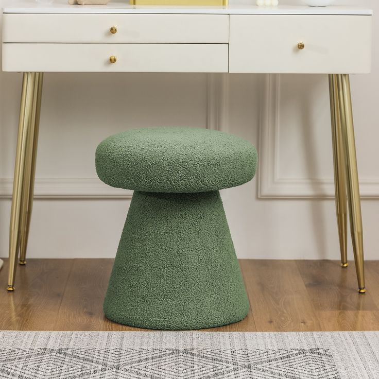 a green stool sits in front of a white desk with gold legs and a mirror