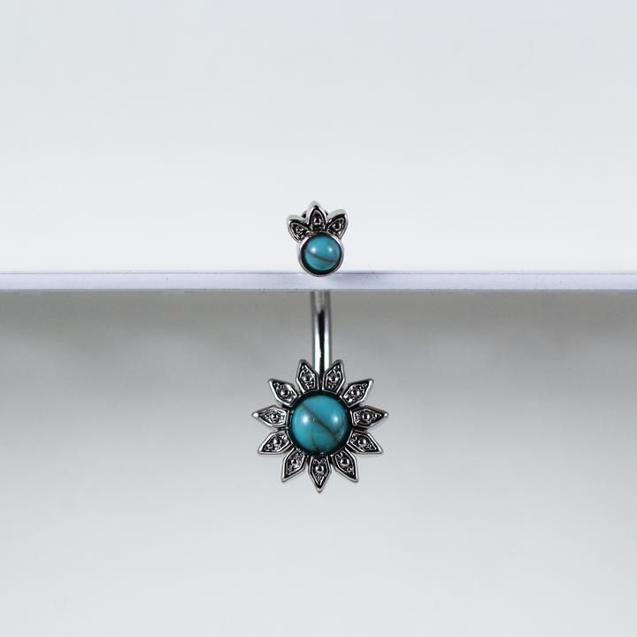 two pairs of earrings with turquoise stones on them sitting on a white surface in front of a mirror