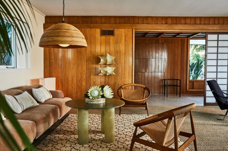 a living room filled with furniture and wooden paneled walls next to a dining table