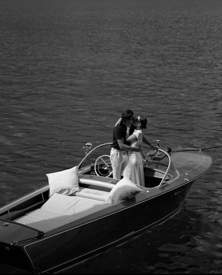 black and white photograph of two people in a boat on the water with their arms around each other