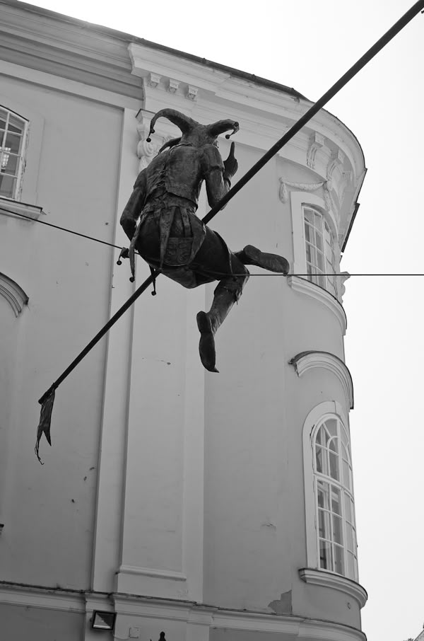 a statue of a man riding on top of a pole in front of a building