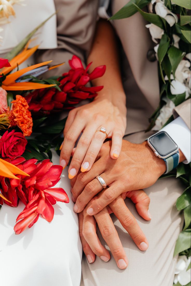 two people holding hands with flowers around them