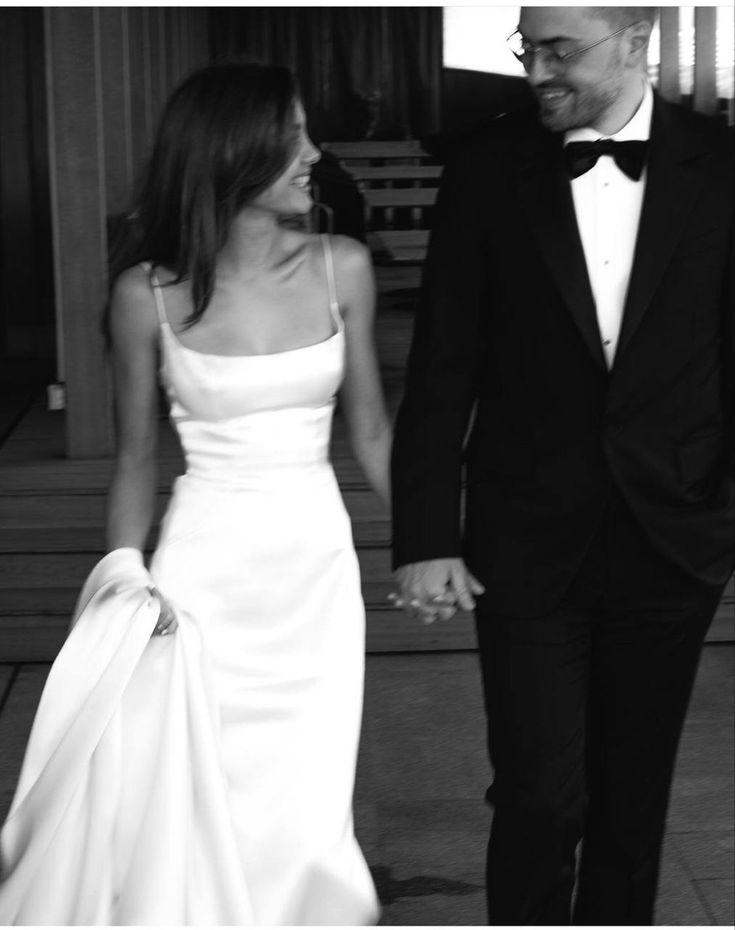 a man and woman in formal wear holding hands