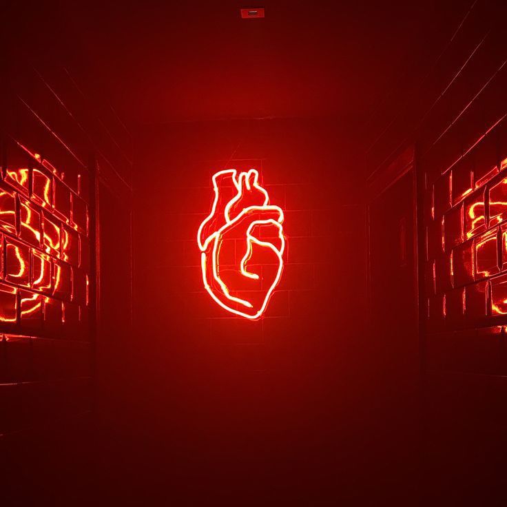 a red neon sign with a human heart on it's side in a dark room