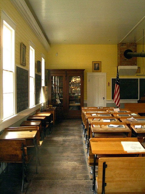 an empty classroom with desks and american flag