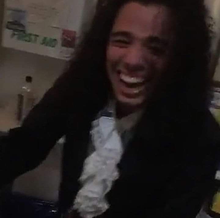 a man with long hair is laughing in the kitchen