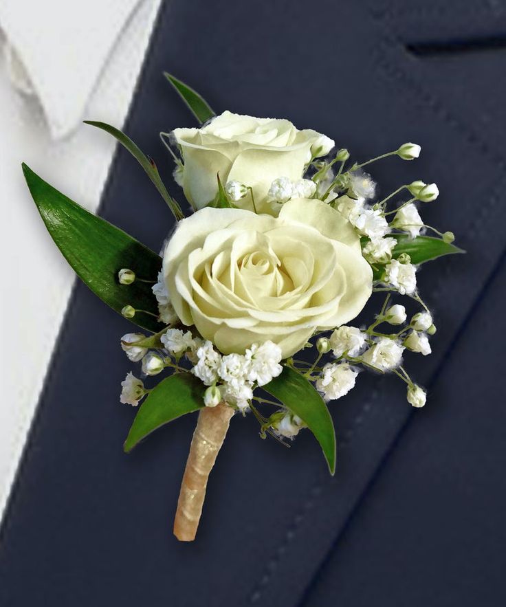 a boutonniere with white roses and baby's breath flowers on it