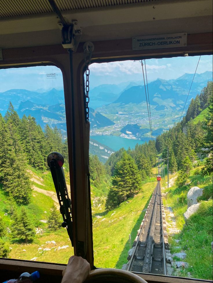 a view from the inside of a train looking down on a valley and mountains in the distance