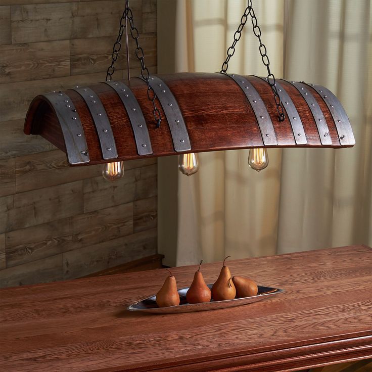 a wooden table topped with three pears under a light fixture hanging from the ceiling