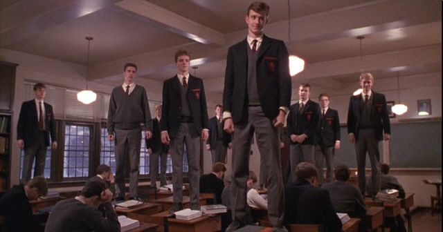 a group of young men standing on top of desks