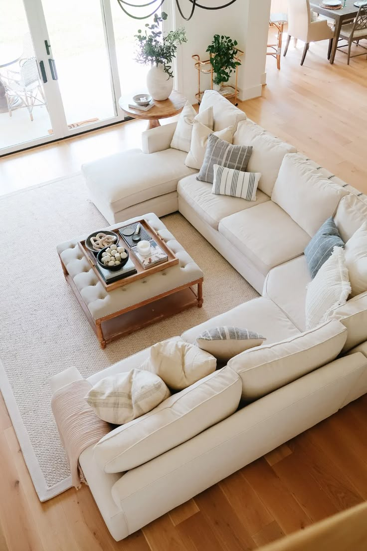 a living room filled with lots of furniture and a large white couch sitting on top of a hard wood floor