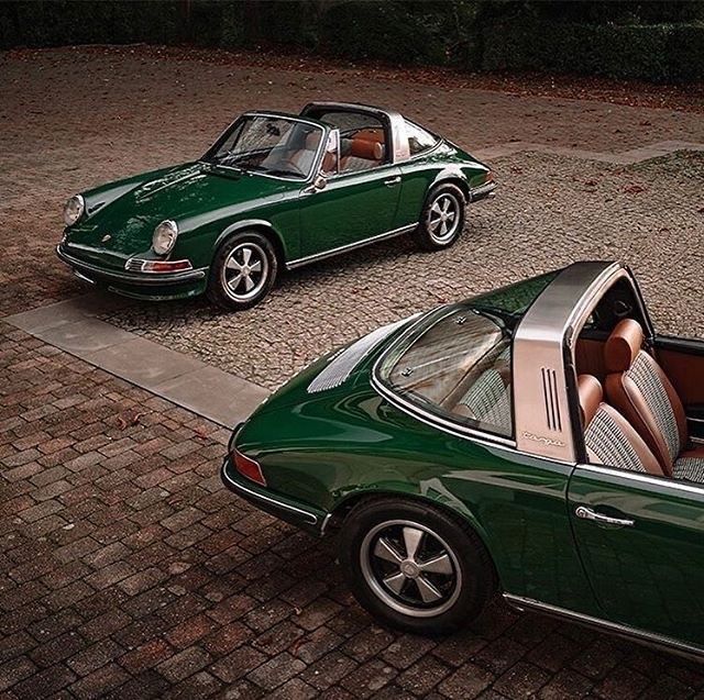 two cars parked next to each other on a cobblestone street with trees in the background