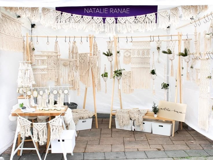 a table and chairs in front of a white tent with macrame hanging from it