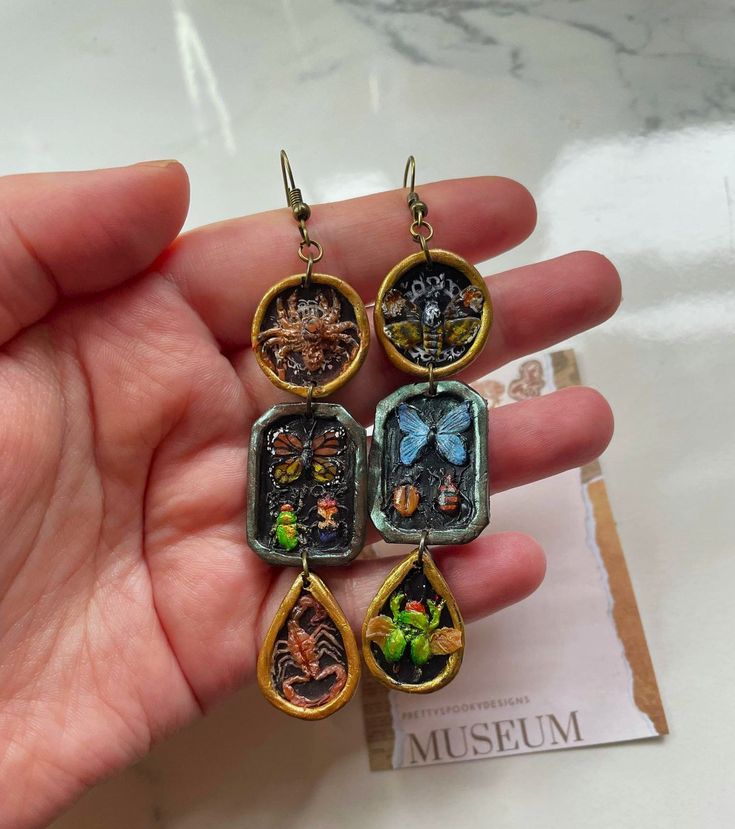 a person holding some kind of earrings with pictures on the front and back of them