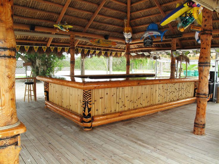 an outdoor bar is decorated with wooden posts and wood planks, along with toy airplanes hanging from the roof