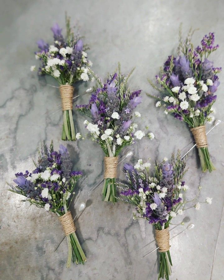 four bouquets of lavender and white flowers tied to twine on a marble surface