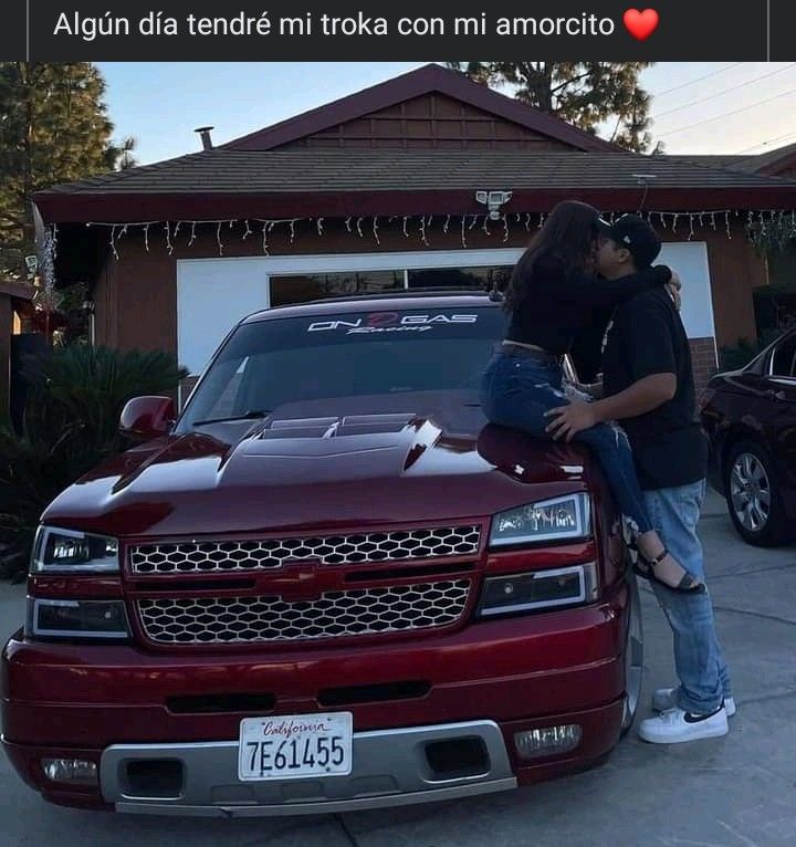 two people standing on the hood of a red truck