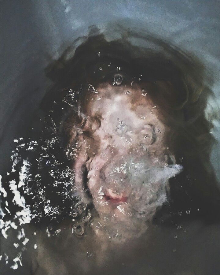 the reflection of a woman's face in water, with bubbles coming out of her mouth