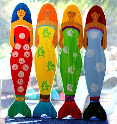 three mermaid dolls sitting next to each other on a window sill in front of a house