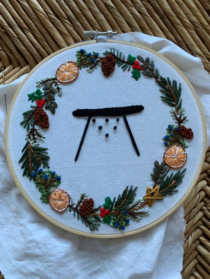 an embroidered christmas wreath with pine cones and oranges