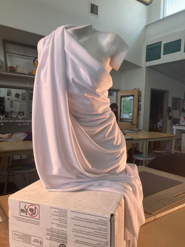 a white cloth draped over a mannequin's head on top of a box