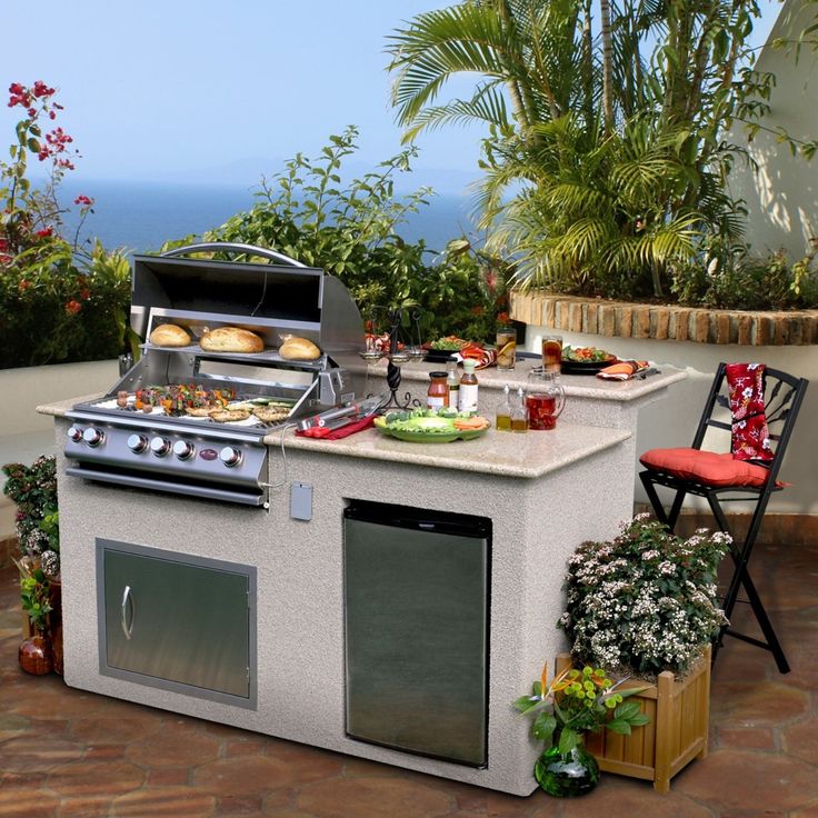 an outdoor bbq grill with two chairs and food on the counter top next to it