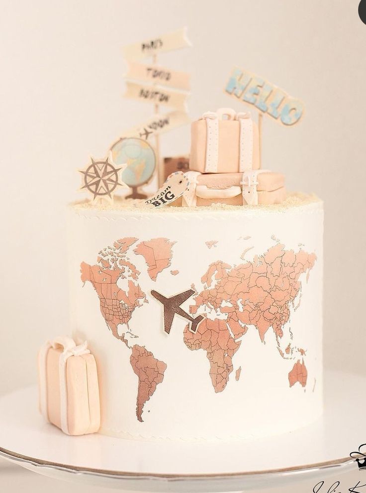 a white cake topped with a world map and lots of small luggage bags on top of it