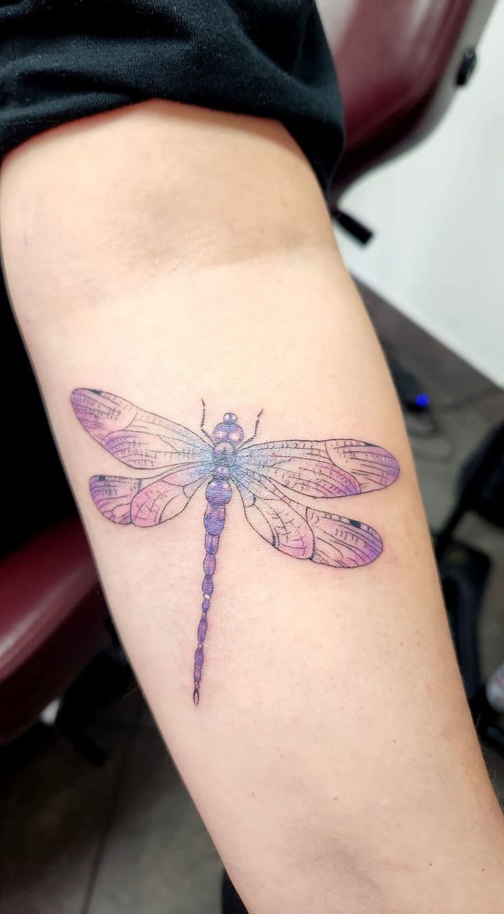 a woman's arm with a dragonfly tattoo on the back of her leg