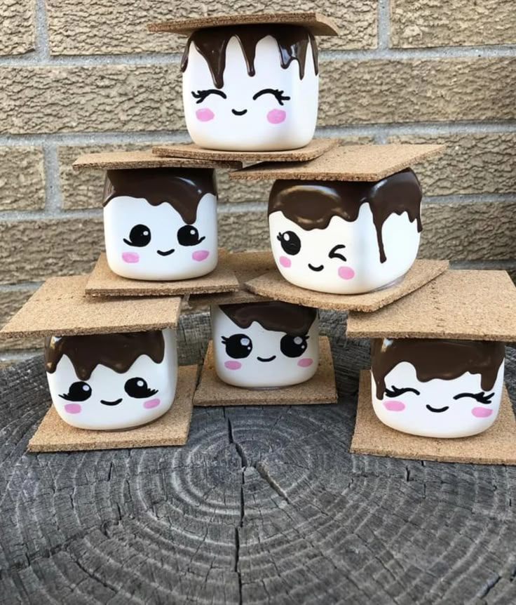 six coffee mugs with faces painted on them are stacked in a cardboard box next to a brick wall