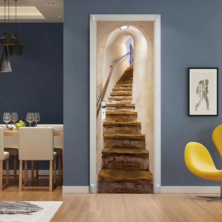 an open door with stairs leading up to a dining room table and yellow chairs in front of it